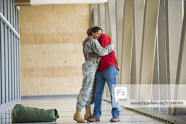 Afroamerikanischer Soldat umarmt Ehemann im Flughafen