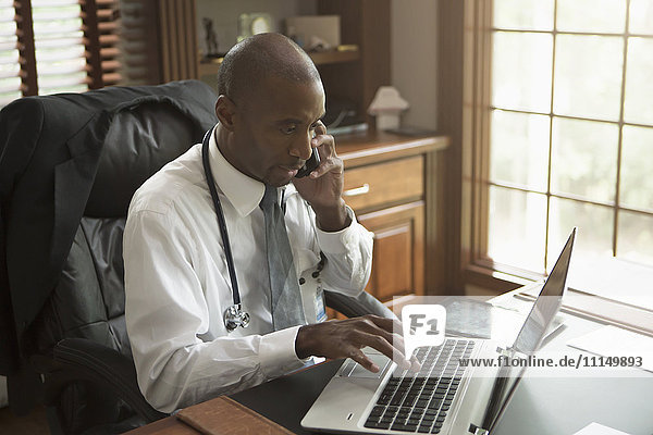 Black doctor talking on cell phone in office