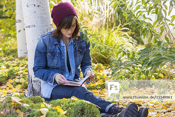 Hispanic woman reading in garden