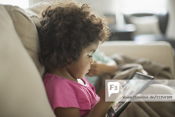 Girl using digital tablet on sofa