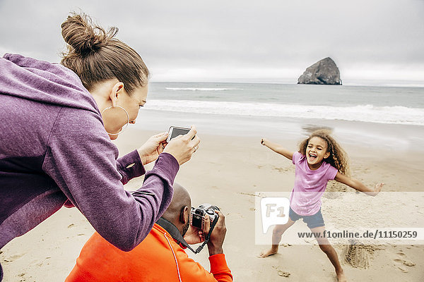 Eltern fotografieren Tochter am Strand