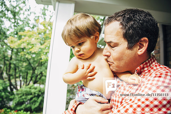 Father holding son on porch