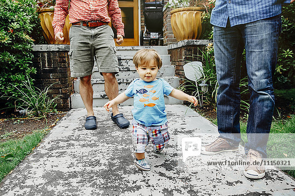 Gay fathers and baby son standing outdoors