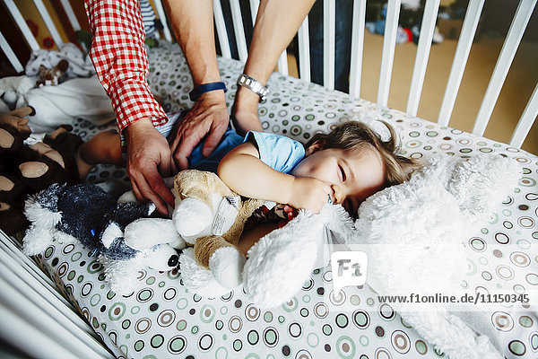 Gay fathers tickling baby son in crib