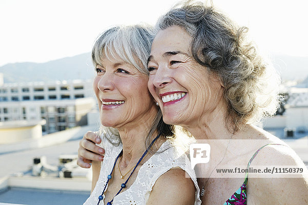Gemeinsam lächelnde Frauen auf einem städtischen Dach