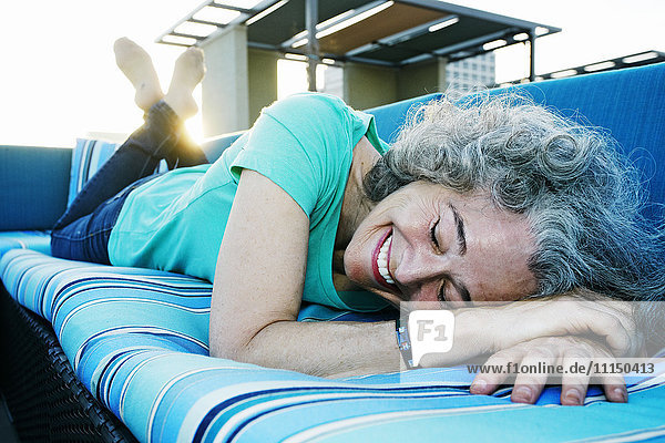 Caucasian woman relaxing on sofa on urban rooftop