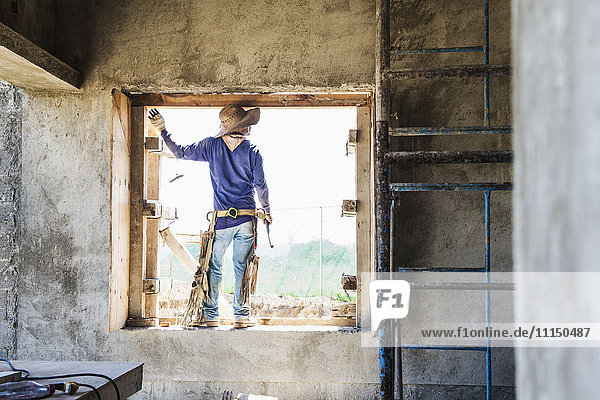 Hispanischer Bauarbeiter in einem Fenster auf der Baustelle