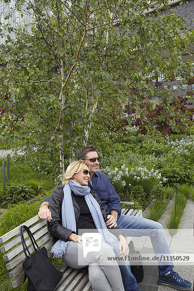 Kaukasisches Paar entspannt sich auf einer Bank im Park