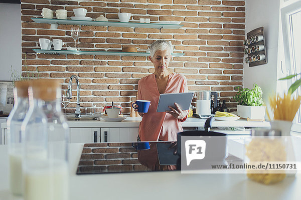 Older Caucasian woman using digital tablet in kitchen