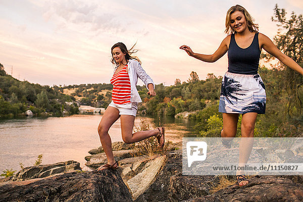 Caucasian teenage girls running on riverbank