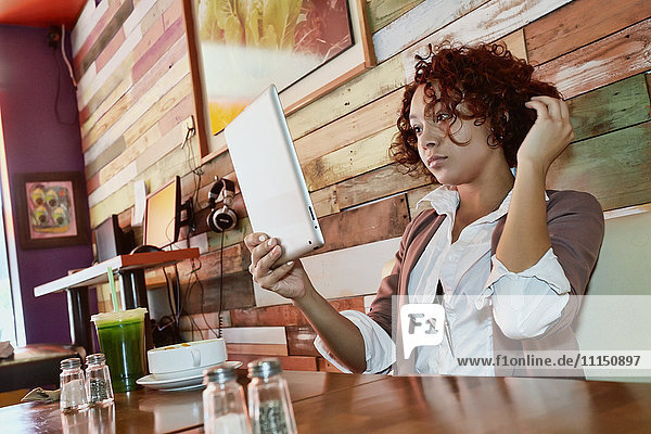 Gemischtrassige Frau benutzt Tablet-Computer in einem Café