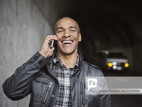 Black man talking on cell phone in urban tunnel