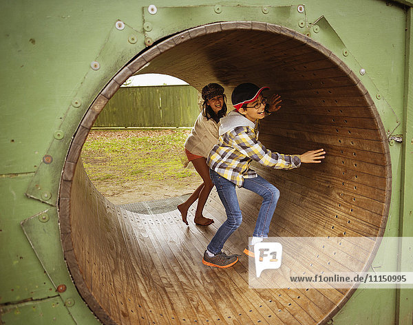 Mixed race children playing in wheel in playground
