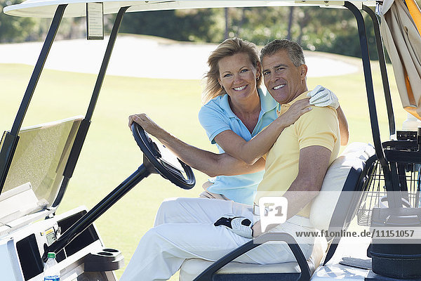 Kaukasisches Paar umarmt sich im Golfwagen auf dem Golfplatz