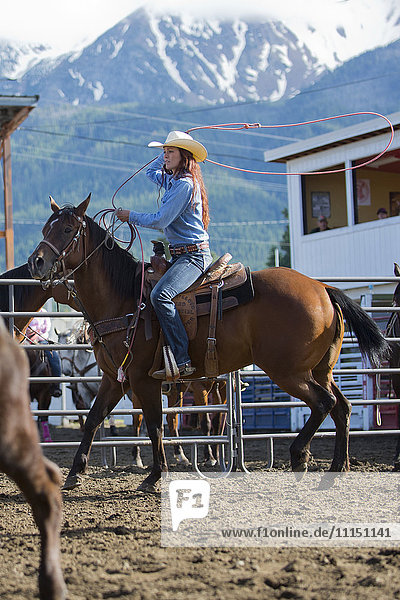 Caucasian cowgirl riding horse in rodeo on ranch