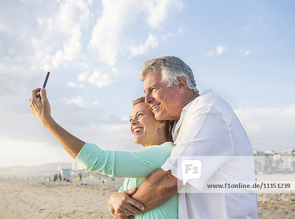 Kaukasisches Paar macht Handy-Selfie am Strand