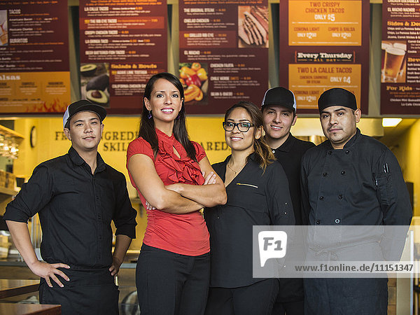 Hispanic business owner and employees smiling in cafe