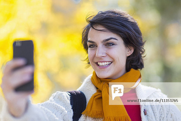 Mixed race woman taking cell phone selfie outdoors