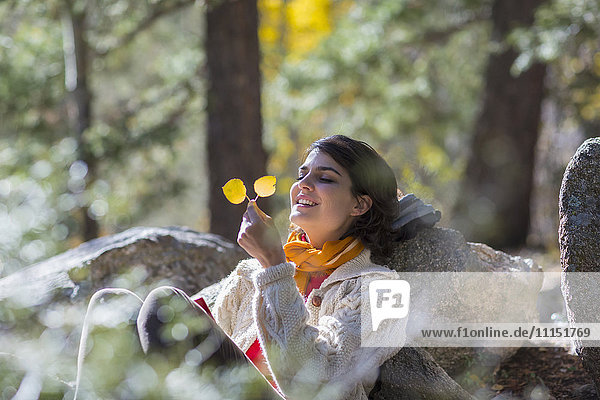 Gemischtrassige Frau bewundert Herbstblätter im Wald