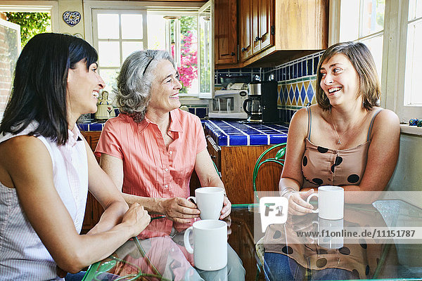 Caucasian mother and daughters drinking coffee in kitchen