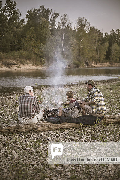 Drei Generationen kaukasischer Männer entspannen sich am Lagerfeuer