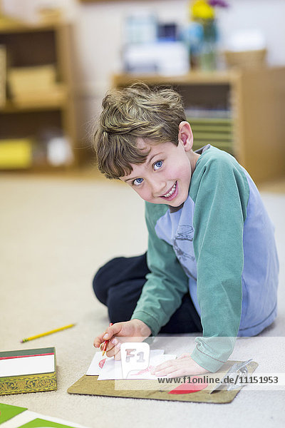 Lächelnder Junge beim Zeichnen im Klassenzimmer