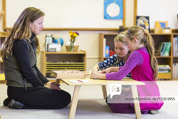 Montessori teacher helping students in classroom