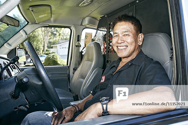 Pacific Islander plumber smiling in van