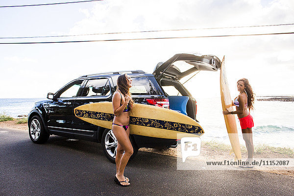Surfer entladen Surfbretter aus einem Auto in Strandnähe