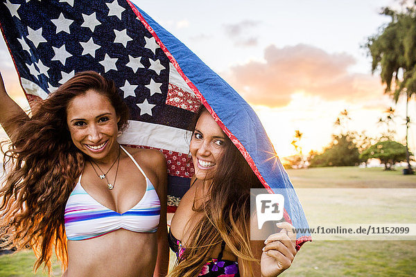 Frauen unter amerikanischer Flagge stehend bei Sonnenuntergang