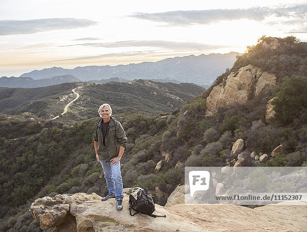 Older Caucasian man standing on rocky hilltop
