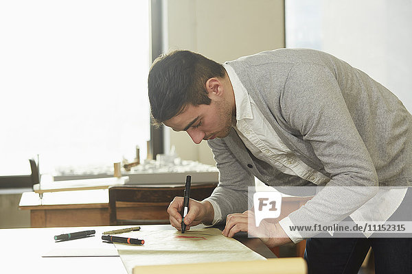 Kaukasischer Geschäftsmann schreibt am Schreibtisch im Büro