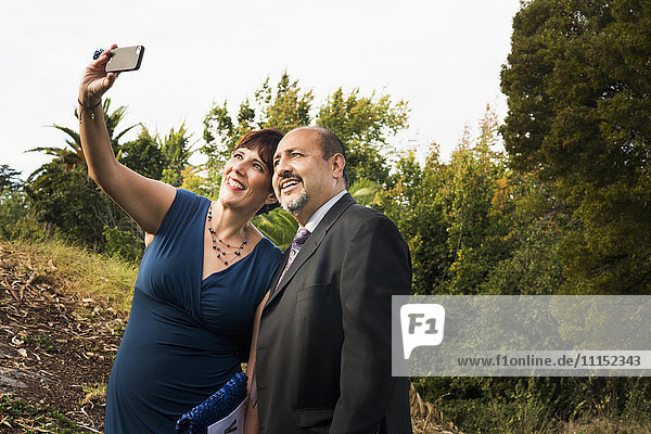 Hispanisches Paar macht Handy-Selfie in formeller Kleidung