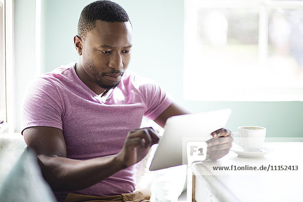 Black man using digital tablet at breakfast