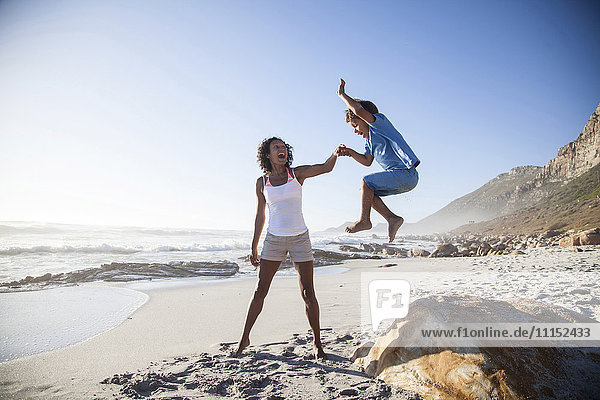 Mixed race mother and son playing on beach