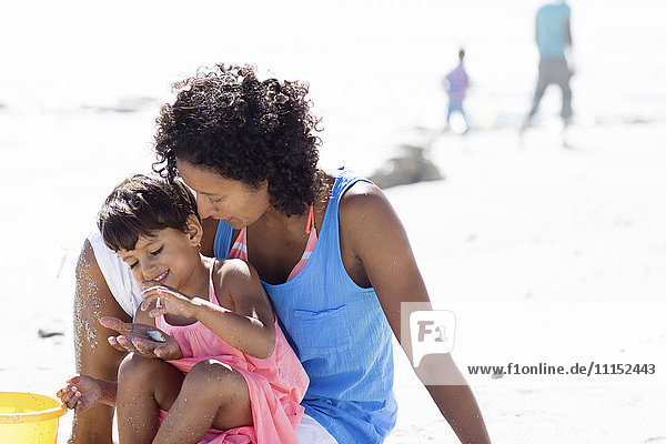 Gemischtrassige Mutter und Tochter spielen am Strand