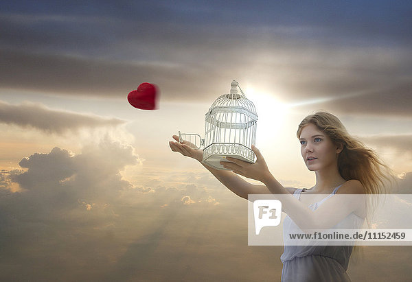 Caucasian woman releasing heart from birdcage