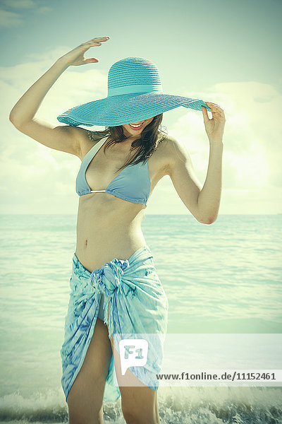 Kaukasische Frau trägt Bikini und Sonnenhut am Strand