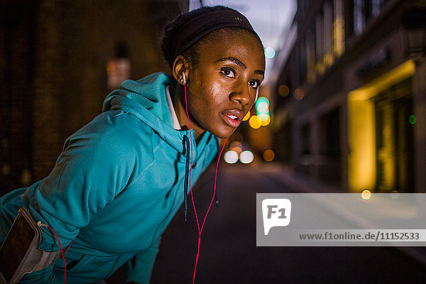 Black runner resting on city street at night
