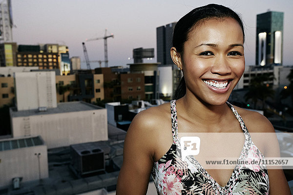 Gemischtrassige Frau lächelt auf einem städtischen Hausdach