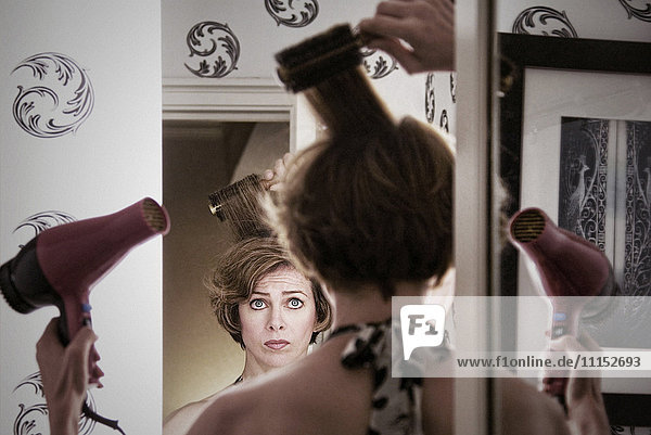 Überwältigte kaukasische Frau beim Frisieren ihrer Haare