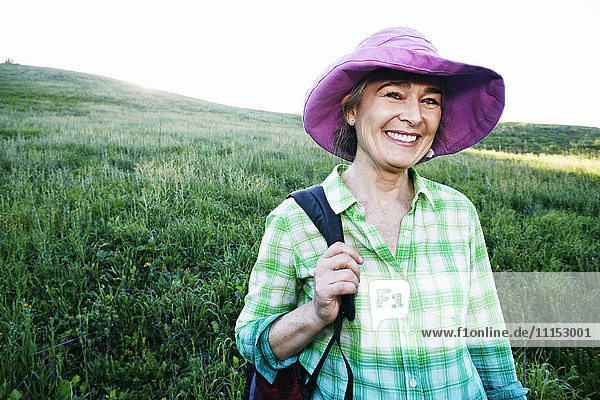 Ältere kaukasische Frau lächelnd auf grasbewachsenem Hügel