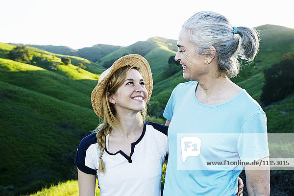 Caucasian mother and daughter smiling on rural hilltop