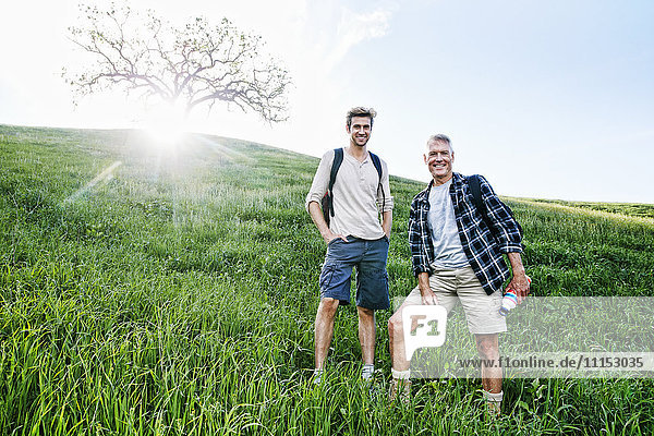 Caucasian father and son standing on grassy hillside