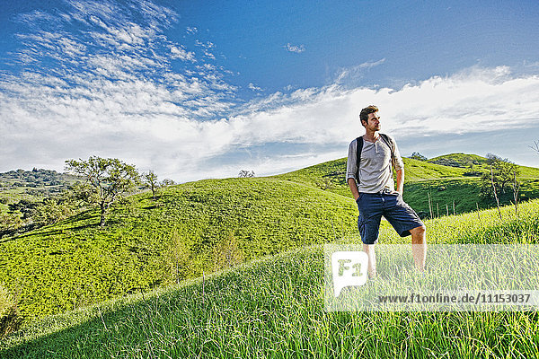 Kaukasischer Mann steht auf einer ländlichen Hügelkuppe