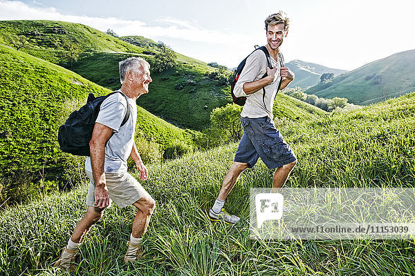 Caucasian father and son walking on grassy hillside