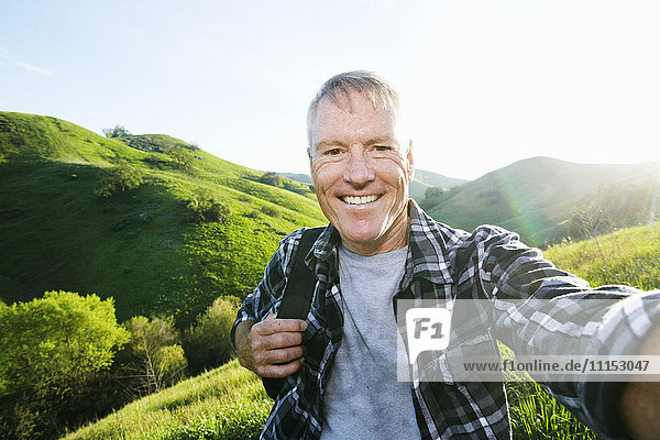 Older Caucasian man taking selfie on rural hilltop
