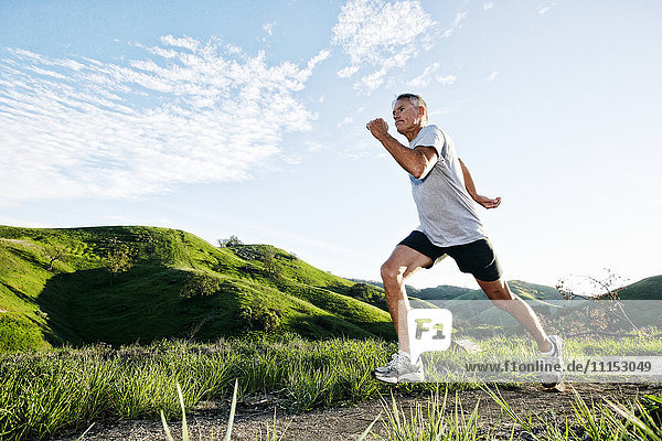 Older Caucasian man jogging on dirt path