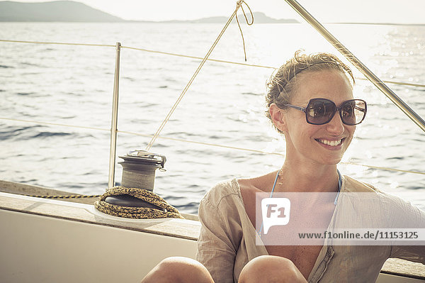 Lächelnde kaukasische Frau sitzt auf dem Bootsdeck