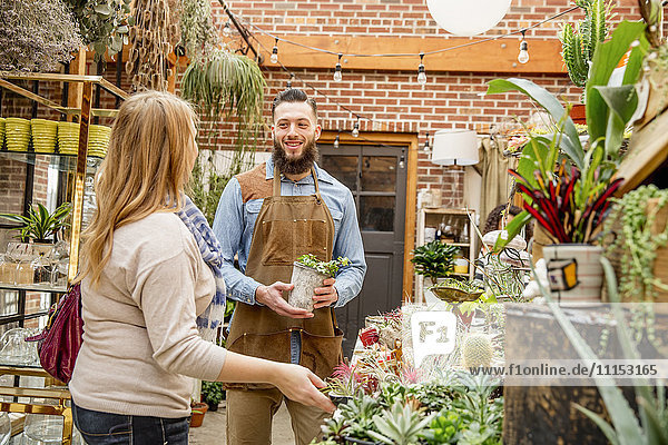 Caucasian employee helping customer in plant nursery